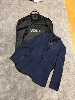 Marinblå kavaj These Glory Days - Snygg marinblå kavaj från These Glory Days med klassisk tvåknappsdesign och smal passform. Tillverkad i ett slätt tyg med diskreta fickor och helfodrad insida. Perfekt för dig som vill ha en stilren och modern look. Finns ingen storlekslapp men passar S 