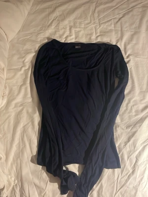 Mörkblå långärmad topp från Bik Bok - Säljer en mörkblå långärmad topp från Bik Bok med rundad halsringning. Toppen är i mjuk och stretchig bomull, perfekt för att styla med jeans eller kjol. Enkel och stilren design som funkar till många olika looks. Toppen har ett litet hål på framsidan som knappt syns