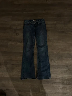 Blå bootcut jeans från Gina Tricot - Säljer ett par blå bootcut jeans från Gina Tricot, modell perfect jeans. Klassisk femficksdesign med snygga detaljer på bakfickorna och slitningar för en cool look. Jeansen har normal passform och är tillverkade i tåligt denimtyg.