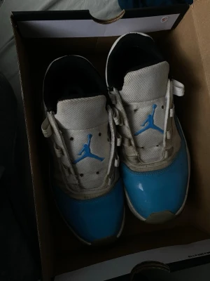 Nike Air Jordan 11 Low UNC blå/vit - Säljer ett par Nike Air Jordan 11 Low UNC i blått och vitt. Skorna har den klassiska Jumpman-loggan i ljusblått på plösen och hälen, vit ovandel i skinn och mesh samt blå lackad tå och sidor. Svart innerfoder och vita snören. Box medföljer. Jag har lådan till storleken är 36.5 men passar 37 också använd några ggr men blivit för små döm är lite smutsiga som ni ser på bilden och jag köpte dom för 1150kr