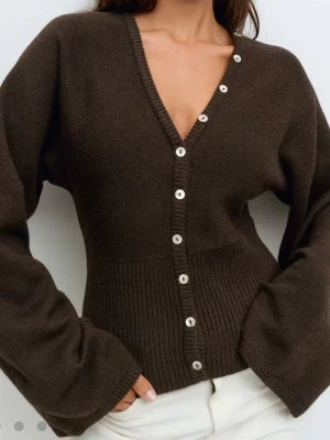 Brun kofta med v-ringning från Gina Tricot - Snygg brun kofta från Gina Tricot med v-ringad hals och vita knappar längs hela framsidan. Ny och oanvänd