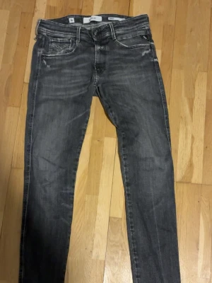 Replay Anbass svarta slim jeans - Säljer ett par Replay Anbass jeans i svart tvätt med snygga slitningar och klassiska fem fickor. Jeansen har slim passform och är tillverkade i mjukt jeansmaterial med stretch. Perfekta för dig som gillar en modern och stilren look.