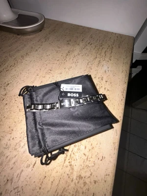 Silver länkarmband BOSS - Snyggt silverarmband från BOSS med stilren design och logotyp på spännet. Armbandet levereras med original ask, påse, lapp och kort. Nypris är ungerfär 1600kr, mitt pris är 899kr! Hör av er vid minsta lilla fundering!