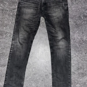 Svarta Indicode jeans, storlek 33/32 - Säljer ett par svarta jeans från Indicode Jeans i storlek 33/32. Modellen har en slim passform med raka ben och klassisk femficksdesign. Jeansen har snygga slitningar och tvättade detaljer som ger en cool look. Perfekt för dig som gillar stilrena och moderna jeans.