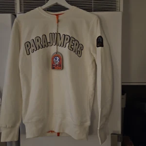 Vit fleece-tröja - Säljer en vit fleece-tröja med broderad logga på bröstet och patch på ärmen. Tröjan har rund hals, långa ärmar och en clean, sportig look. Perfekt för dig som gillar stilrena och bekväma plagg med premiumkänsla. Passar även M!! Helt ny!