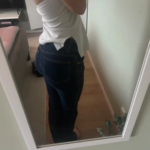Mörkblå lowwaist bootcut jeans med snygga sömmar. Passar S och XS - Snygga mörkblå jeans med bootcut ben och tydliga kontrastsömmar. 