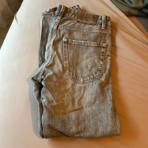 Gråa '90s wide jeans från Bershka - Säljer ett par gråa jeans från Bershka i modellen '90s wide. De har en bred passform och klassisk femficksdesign. Jeansen är tillverkade i denim och har en snygg, ljusgrå tvätt som ger en cool vintagekänsla.