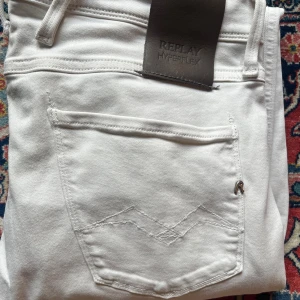 Vita Replay Hyperflex jeans - Säljer ett par vita Replay Hyperflex jeans med klassisk femficksdesign och snygg passform. Jeansen är stretchiga och sitter slim längs benen. Perfekta om du vill ha ett par stilrena och bekväma jeans med modern look.