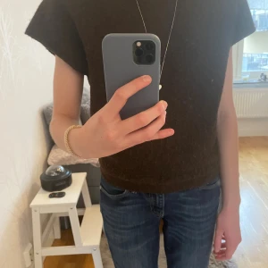 Mörkbrun stickad topp från Nelly - Säljer en mörkbrun stickad topp från Nelly i storlek S. Toppen har en loose passform med korta ärmar och rund hals. Materialet är mjukt och lite fluffigt, perfekt för att ge en chill vibe till din outfit. Enkel och stilren design utan detaljer.