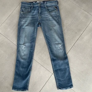 Replay Anbass jeans blå  - Snygga Replay Anbass jeans i blå tvätt med slitningar och klassiska fem fickor. Slim fit-modell och sitter bra på killen på bilden som är ca 185! Storleken är 32/30. Hör av dig vid minsta fundering 