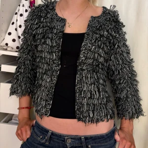 Svart och vit kofta jacka Gina Tricot - Unik svart och vit kofta från Gina Tricot i storlek S. Koftan har ett coolt, stickat loop-mönster som ger en fluffig och trendig look. Modellen är öppen framtill och har trekvartsärmar. Perfekt för dig som vill sticka ut med en annorlunda och snygg jacka.