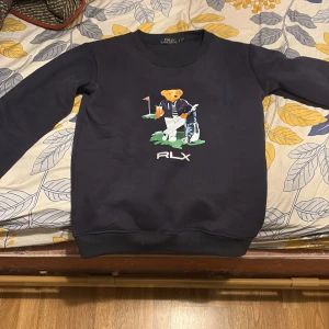 Mörkblå Polo Ralph Lauren tröja S - Mörkblå sweatshirt från Polo Ralph Lauren med ikoniska Polo Bear-trycket på bröstet. Tröjan har rund hals, långa ärmar och RLX-logga under motivet. Perfekt för dig som gillar sportig och preppy stil.