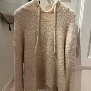 Beige stickad hoodie från Gina Tricot - Mysig stickad hoodie i beige från Gina Tricot. Tröjan har huva med snörning.