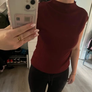 Vinröd strukturerad topp - INTE MIN BILDER! Säljer en vinröd topp med struktur och hög hals. Toppen är ärmlös. Storlek S. Aldrig använd.