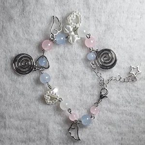 Pastelligt armband med pärlor och berlocker - .