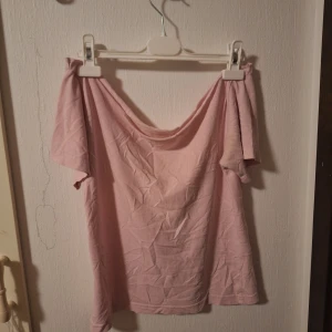 Ljusrosa offshoulder topp - Säljer en ljusrosa offshoulder topp med korta ärmar. Toppen har en mjuk och avslappnad passform och är tillverkad i bomull. Perfekt för dig som gillar en enkel och feminin stil med lite extra edge tack vare den bara axeln. Har klippt av den själv men inget som märks. Kan skicka bättre bilder om så önskas🥰🫶