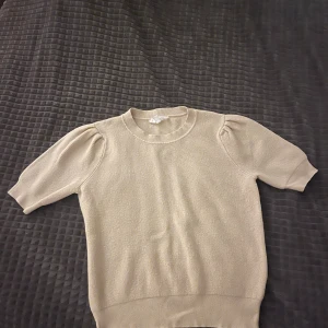 Beige stickad puffärm tröja - Snygg beige stickad tröja med puffärmar och rund hals. Modellen har korta ärmar med lätt rynk vid axlarna. Mjuk och skön kvalitet. Säljer för att den inte kommer till användning längre. Skriv om ni har några frågor😊💕