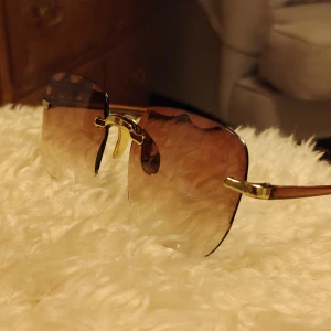 Bruna fyrkantiga solglasögon med guld - Helt nya solglasögon i låda med fyrkantiga, bruna tonade glas och guldfärgade detaljer vid näsbryggan och skalmarna. Glasögonen har en modern, kantig design och transparenta bruna skalmar. Perfekta för dig som vill sticka ut med en trendig accessoar.