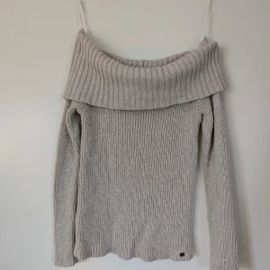 Beige offshoulder stickad tröja Hollister - Supermysig beige stickad tröja från Hollister i storlek S. Tröjan har en bred, ribbad offshoulder-krage och långärmade ärmar. Perfekt för dig som gillar chill och snygg stil med en twist. Ribbad struktur och mjukt material gör den extra skön.