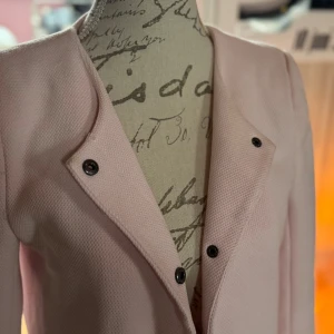 Ljusrosa kappa från ONLY, stl S - Säljer en ljusrosa kappa från ONLY i storlek S. Jackan har lång ärm, knappar framtill och en stilren, rak passform. Materialet är strukturerat och känns mjukt. Perfekt för dig som vill ha en clean och snygg look.