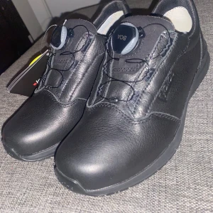 Svarta BOA sneakers i skinn - OANVÄNDA! Svarta sneakers från BOA med rund tå och platt sula. Skorna har ett innovativt snörningssystem med vridknapp för enkel justering. Tillverkade i slitstarkt skinn med vadderad insida och mönstrad yttersula för bra grepp. Perfekt för dig som gillar stilren och funktionell design.