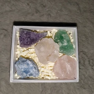 Sten- och kristallkit - Ett vackert kit med fem råa kristaller i olika färger, perfekt för samlare eller dekoration. Stenarna levereras i en elegant presentask med skyddande fyllning. Perfekt som gåva eller för egen användning. Inga synliga defekter eller skador.