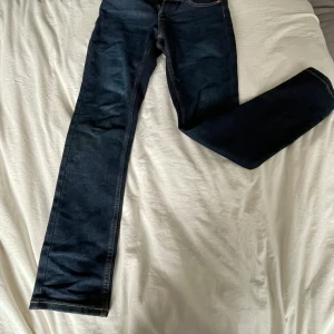 Levi's mörkblå jeans slim fit - Mörkblå jeans från Levi's i slim fit-modell med klassiska kontrastsömmar och dragkedja. Jeansen har 4 fickor och en rak, smal passform som sitter snyggt. Perfekta för dig som gillar en stilren och tidlös look.