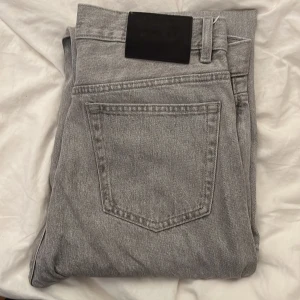 Grå jeans från Zara, strl 40 ( ish 32 längd 32 midja - Snygga grå jeansbyxor från Zara i storlek 40. Klassisk femficksmodell med svart patch bak i midjan där de står Zara man. Jeansen har rak passform och är tillverkade i slitstarkt bomullsmaterial. Perfekt för dig som gillar stilrena och neutrala färger. Typ aldrig använda då dom var lite för stora i midjan tyvärr.