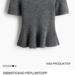 Grå ribbstickad peplumtopp - Superfin grå peplumtopp i ribbstickat material med korta ärmar och markerad midja som ger en snygg siluett. Toppen har en lätt utsvängd volang nertill och är perfekt för dig som gillar en trendig och bekväm look.