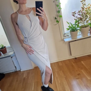 Beige långklänning - Beige långklänning med cut out vid bysten samt hög slits. Ribbat tyg och detalj vid ena höften. Så härlig uppdressad vardagsklänning eller downdressed högtid 🍁 inga tecken på användning 🌻Återuppladdad för fri frakt. Jag har mycket annat uppe på sidan, både herr och damkläder. Köp gärna bundle för att få rabatt 🤗