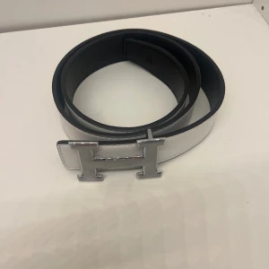 Bälte - Ett vit bälte med silvrigt H, den är helt ny och är i 105 cm. Pris kan diskuteras och skriv om du har några frågor. 