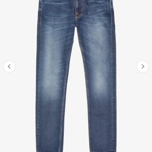 Nudie jeans - Snygga blå jeans med raka ben och diskreta slitningar framtill. Klassisk femficksmodell med orange sömmar och detaljerade bakfickor. Jeansen har normal passform och är tillverkade i mjukt denimtyg som ger en avslappnad look.
