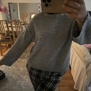 Grå stickad tröja med breda ärmar - Mysig grå stickad tröja med breda, raka ärmar och rund hals. Enkel och stilren design som passar perfekt till chill dagar. Materialet är mjukt och ger en skön känsla mot huden. Perfekt att matcha med jeans eller mjukisbyxor.