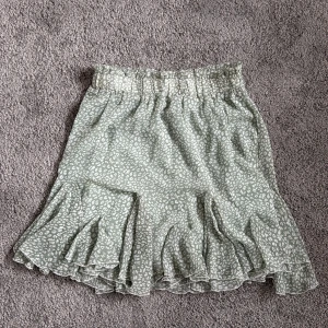 Ljusgrön volangkjol med vita leopardmönster från Voyelles i storlek M - Supersöt knäkjol från Voyelles i ljusgrönt med vitt leopardmönster. Kjolen är helt oanvänd, då den var lite flr stor för min midja, Kjolen har resår i midjan och flera lager volanger som ger en skön känsla. Materialet är lätt och mjukt, som silkes material, och är perfekt för dig som vill känna dig bekväm och samtidigt uppklädd. 