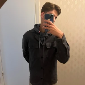 Mörkblå overshirt från Jack & Jones - Snygg mörkblå overshirt från Jack & Jones Premium med klassisk krage och två bröstfickor med knappar. Skjortan har långa ärmar och är tillverkad i mjuk bomull.. Pris kan diskuteras har knappt använt den för jag köpte en annan.