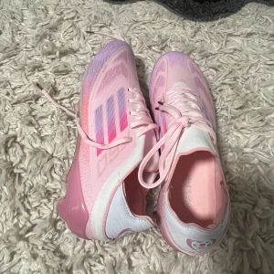 Adidas F50 fotbollskor  - Säljer ett par snygga fotbollsskor i storlek 42. Skorna är i en ljusrosa färg med lila och rosa detaljer samt klassiska Adidas-ränder på sidan. Helt nya. Ingen kartong!