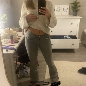 Grå bootcut jeans från Gina - Snygga grå jeans från ginamed bootcut passform och låg midja. Klassisk femficksmodell med knapp och dragkedja framtill. Jeansen har en stilren look och är tillverkade i mjukt jeanstyg som sitter bekvämt. Perfekta för dig som gillar en avslappnad men trendig stil.