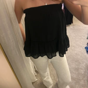 Svart volangkjol i chiffong - Säljer en svart kortkjol med volangkant i lätt och flödande chiffongmaterial. Kjolen har en enkel, stilren design och sitter bekvämt i midjan. Perfekt för dig som gillar en feminin och trendig look med lite extra rörelse i tyget. Passar perfekt som topp!