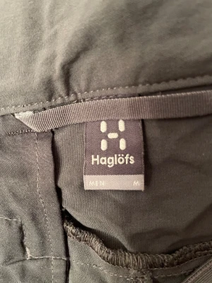 Grå cargopants från Haglöfs, M - Säljer ett par grå cargopants från Haglöfs i storlek M. Byxorna har flera praktiska fickor, bland annat med dragkedja på benet, och är tillverkade i slitstarkt syntetmaterial. Perfekta för dig som gillar outdoor och funktionella kläder.