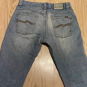 Nudie Jeans Vintage - Säljer ett par klassiska Nudie Jeans i ljusblå tvätt, raka ben och snygga slitningar. Jeansen kan räknas som vintage då de är från 2001 eller 2002, men de är i bra skick och har inga större tecken på användning.