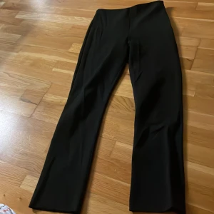 Svarta kostymbyxor Gina Tricot 34 - Snygga svarta kostymbyxor från Gina Tricot i storlek 34. Byxorna har hög midja, raka ben och diskreta fickor bak. Materialet är mjukt och har en lätt stretch för extra komfort. Perfekta för en clean och stilren look.