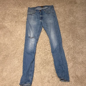 Lee  ljusblå skinny jeans W30 L34 - Säljer ett par Lee Luke jeans i ljusblå tvätt med skinny passform. Klassisk femficksmodell, dragkedja och knapp i midjan. Jeansen har en liten sliten detalj på ena benet för en cool look. Perfekt för dig som gillar smalare jeans.