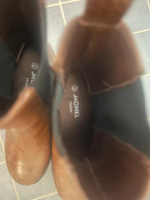 Bruna chelsea boots från Monki - Snygga bruna chelsea boots från Monki med croco-mönstrad yta och kraftig platt sula. Bootsens material är veganskt syntet och de har rund tå samt elastiska paneler på sidorna för enkel påtagning. Perfekt för dig som gillar chunky stil och detaljer.
