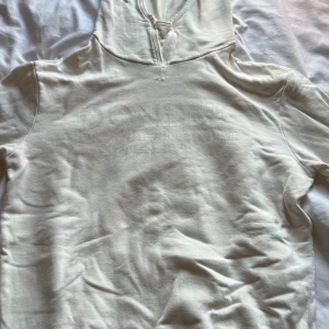 Vit hoodie från Dondup med huva - Säljer en stilren vit hoodie från Dondup med broderad logga framtill. Tröjan har huva med snörning och är tillverkad i mjuk bomull. Perfekt för dig som gillar minimalistisk design och italiensk kvalitet. Långärmad och med klassisk passform.