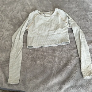 Ribbad croppad långärmad topp Bik Bok - Säljer en ljusbeige ribbad croppad topp från Bik Bok i storlek XS/S. Toppen har lång ärm, rund hals och diskret randigt mönster. Perfekt för dig som gillar stilrena och enkla plagg med en modern passform.