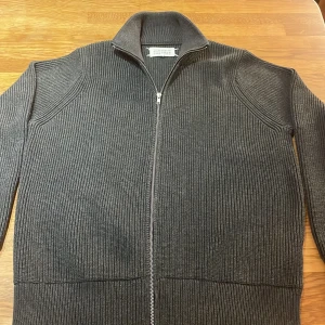 Maison Margiela - Säljer en grå ribbstickad kofta från Maison Margiela, aldrig använd. Perfekt för dig som gillar stilrena och coola detaljer. Tröjan passar M till L