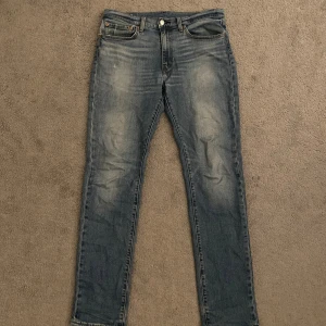 Levi's 511 34/34 - Säljer ett par Levi's 511 jeans i klassisk blå tvätt med snygga slitningar och lätt faded effekt. Modellen har fem fickor, knapp och dragkedja fram samt Levi's Premium-märke på insidan. Passformen är slim och benen är raka.