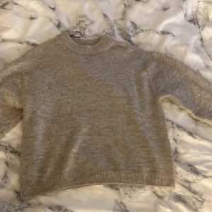 Beige stickad tröja från H&M - Mysig beige stickad tröja från H&M i storlek XS. Tröjan har en rund hals med ribbad kant och långa ärmar med ribbade muddar. Perfekt för dig som gillar enkel och clean stil med neutrala färger.