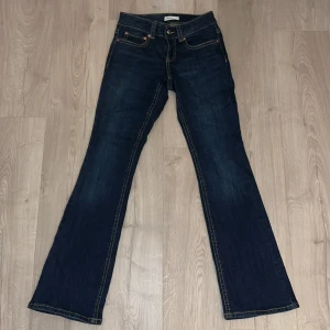 Bootcut jeans från Gina Tricot, blå - Snygga mörkblå bootcut jeans från Gina Tricot, modell Perfect Jeans. Klassisk femficksdesign med kontrastsömmar och knappstängning. Jeansen har låg midja och är tillverkade i jeansmaterial med stretch för skön passform.