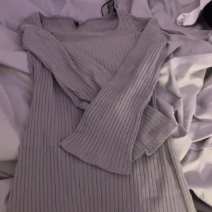 Grå ribbad klänning från H&M Divided - Säljer en ljusgrå ribbad klänning från H&M Divided i storlek S. Klänningen har långa ärmar och är tillverkad i ett mjukt, stretchigt material som sitter snyggt på kroppen. Perfekt för dig som gillar enkel och stilren design.